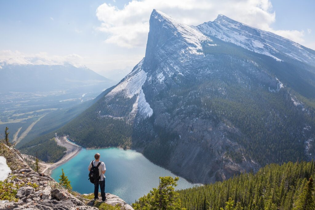Un homme sur une falaise de montagne observe la faune et la flore d'un magnifique paysage ensoleillé.